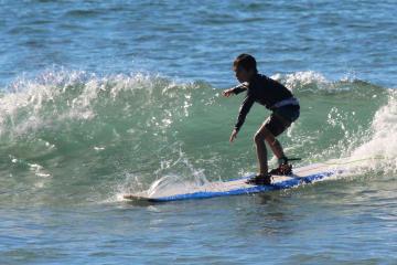a small girl riding a wave on a surfboard in the ocean